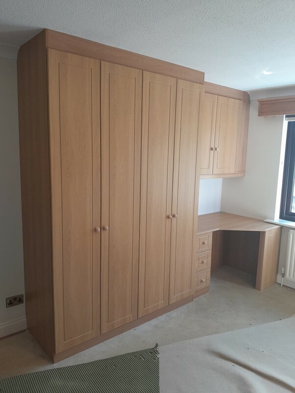 Fitted bedroom furniture with in-built wardrobes and overhead cupboards.