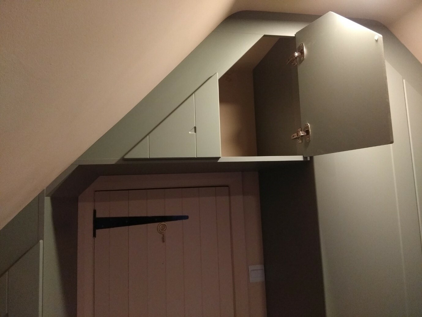 Angled loft room with sage green fitted wardrobes with all doors open showing ample storage space