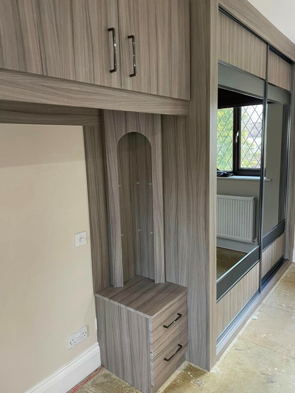 Fitted bedroom in Southampton with over bed storage and fitted bedside table and storage above in dark wood with fitted glass door wardrobes in background