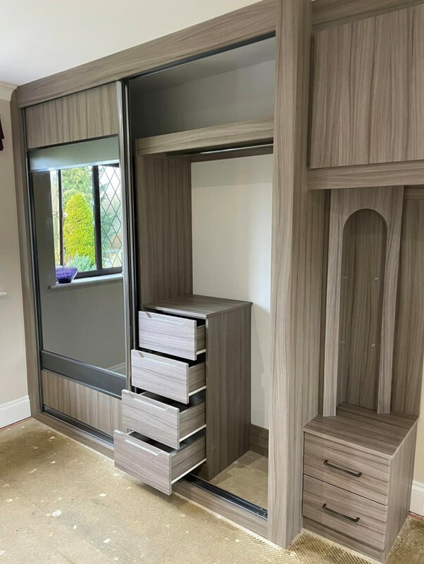 Open sliding fitted wardrobe showing fitted drawers and hanging rail on inside 